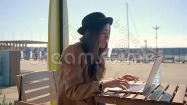 年轻的黑发女人坐在街上用笔记本电脑和<strong>无线上网</strong>聊天
